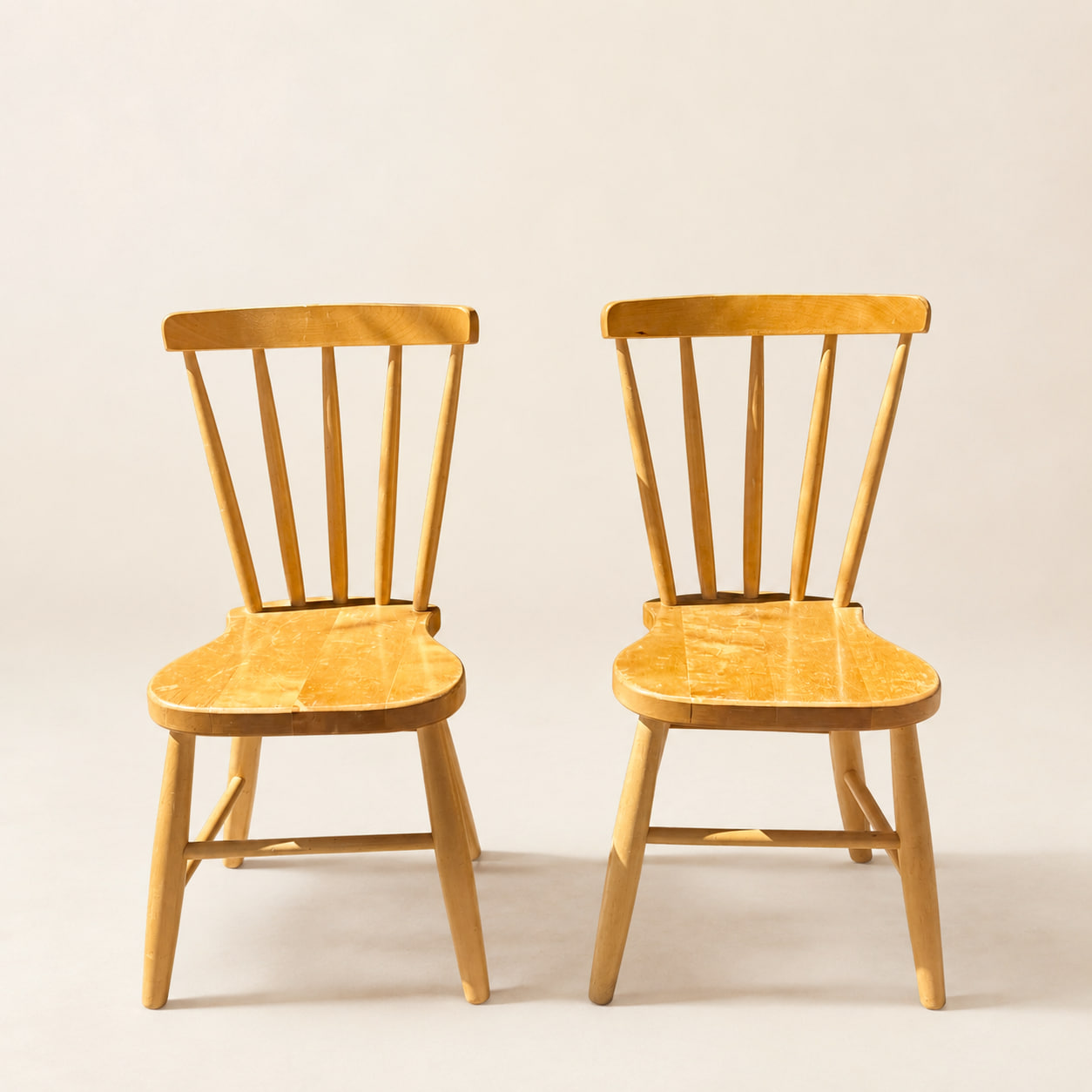 Ett par klassiska barnstolar i björk med spjälat ryggstöd och tidlös skandinavisk design. Stabilt och bra skick med mindre spår av användning. Säljs som par.